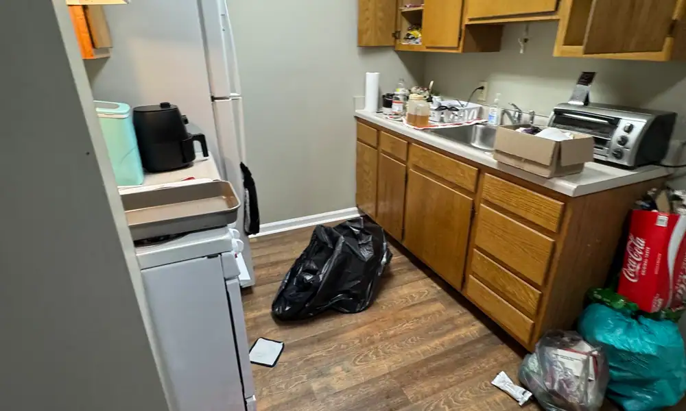 Kitchen with a refrigerator and bags left behind