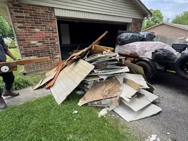 Boards, panels and bagged junk in front of a garage