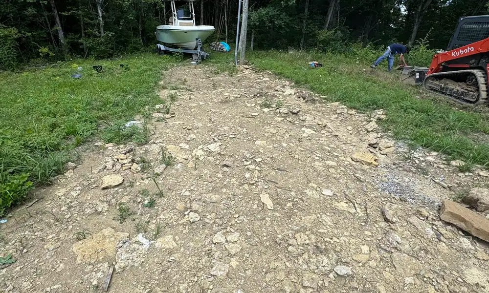 Old drive broken out to bare ground, with a skid steer at work