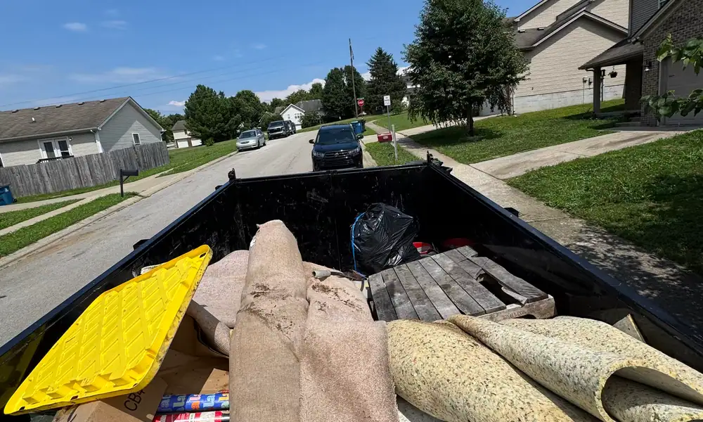 Truck bed loaded with rolled carpet and debris