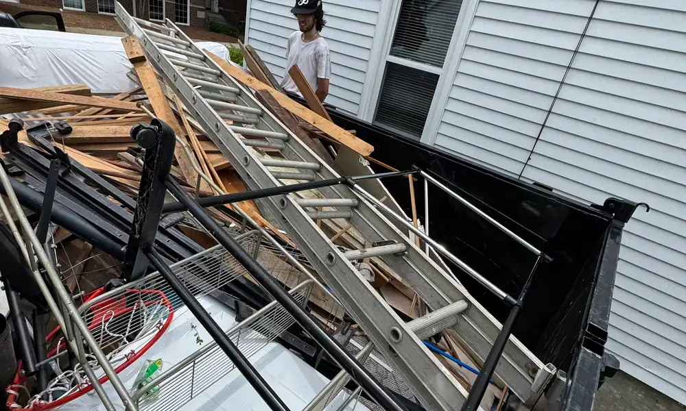 Crew member loading ladders and scrap onto a trailer