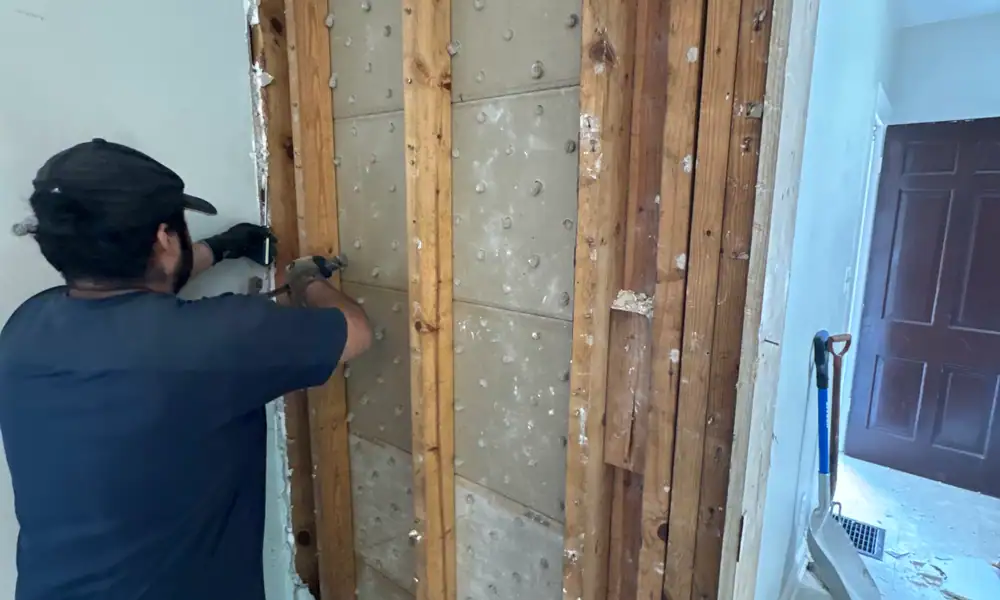 Crew member stripping an interior wall back to the studs
