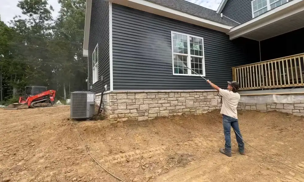 Crew member pressure washing house siding