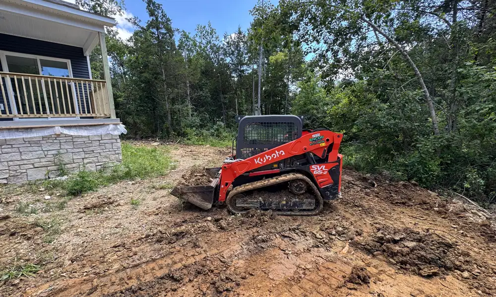 Skid steer on cleared ground beside a house