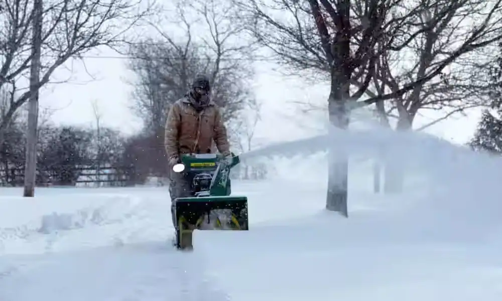 Crew member clearing snow with a snow blower