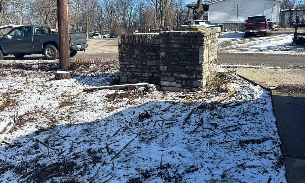 Snow-covered lot entrance beside a brick pillar